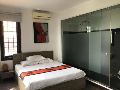 a bedroom with a bed and a glass shower at Ki Nô Homestay in Hoi An