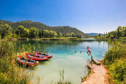 a person jumping into a lake with three boats at Apartment Petar - by the Sea in Gradac