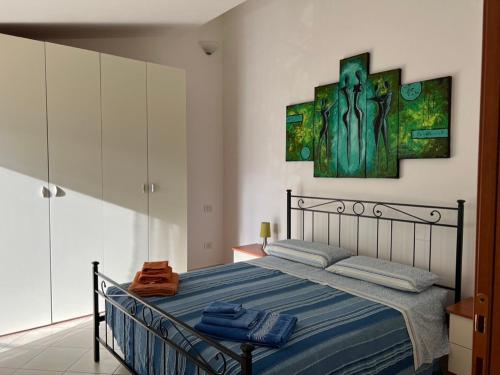 1 dormitorio con 1 cama y una pintura en la pared en Villa Magnolia, en Muravera