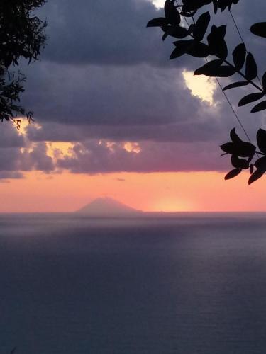 a sunset over the ocean with a mountain in the distance at Villa Panorama in Zambrone