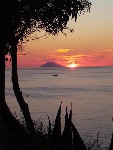 a sunset over the ocean with a boat in the water at Villa Panorama in Zambrone