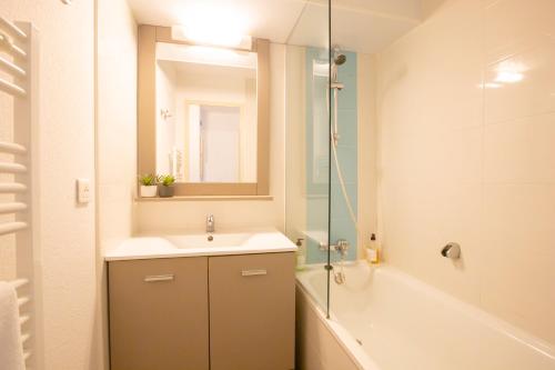 ein Badezimmer mit einem Waschbecken, einem Spiegel und einer Badewanne in der Unterkunft LA SYMPHONIE, PISCINE, PLAGE in Gassin
