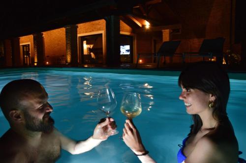 a man and woman drinking wine in a swimming pool at Resort Villa Paola in Longiano