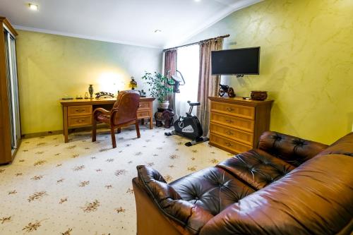 a living room with a leather couch and a desk at Hotel France in Vinnytsya