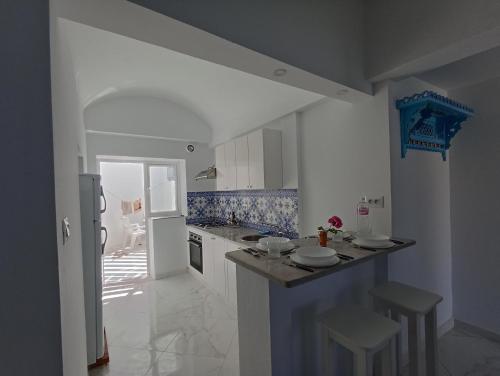 eine weiße Küche mit einer Theke und einem Kühlschrank in der Unterkunft Maison S+1 très bien équipée à 2mn de la plage in Kelibia
