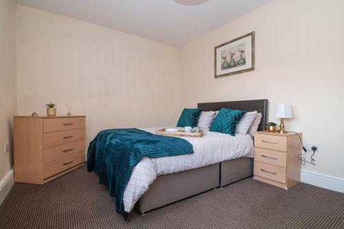 a bedroom with a bed with blue sheets and a dresser at Lovely 1 bed apart.Contractors.NearRussellHillHosp in Brierley Hill