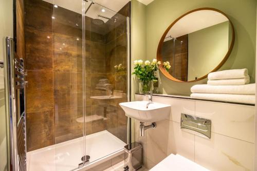 a bathroom with a shower and a sink and a mirror at The Boutique York Garden Studio in York