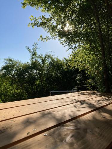 a wooden picnic table with trees in the background at Cabane Bivouac avec échelle à l'ombre des chênes in Idrac-Respailles