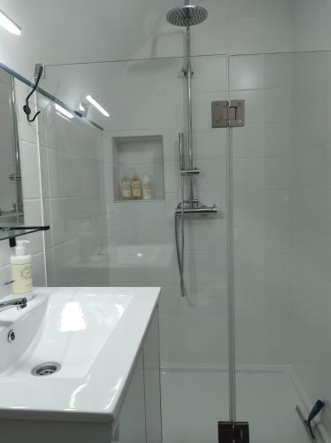 a white bathroom with a shower and a sink at Casa do Bairro - A Gema escondida da Santa Catarina da Fonte do Bispo in Santa Catarina da Fonte do Bispo
