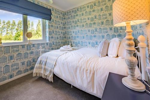 a bedroom with a bed with a lamp and a window at Apartment 4, Hunstanton in Hunstanton