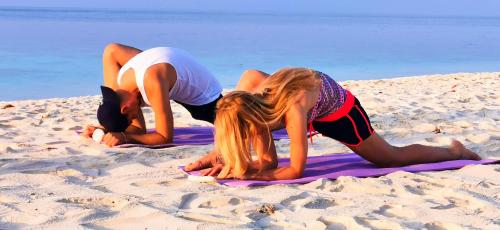 two girls are doing yoga on the beach at Ranthari Hotel and Spa Ukulhas Maldives in Ukulhas