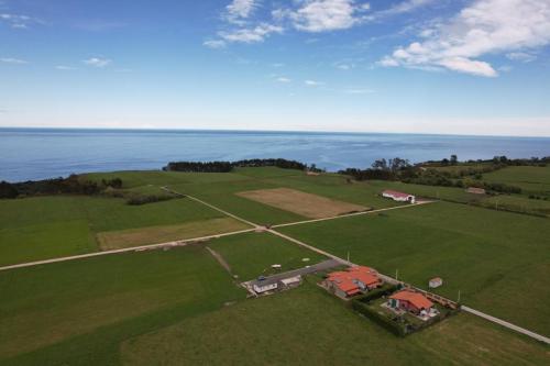 una vista aerea di una casa in un campo con l'oceano di Apartamentos Rurales Miramar a Pimiango