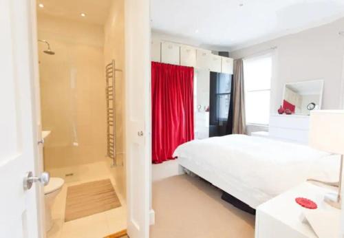 1 dormitorio con cama blanca y cortina roja en Sunny 2 bedroom, 2 bathroom Apartment with Roof Terrace, en Londres