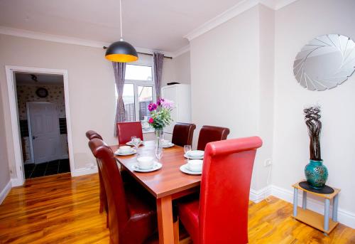 a dining room with a wooden table and red chairs at First house in Kettering