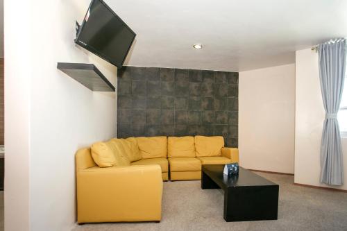 a living room with a yellow couch and a tv at Hotel Euro Confort,Pachuca in Pachuca de Soto