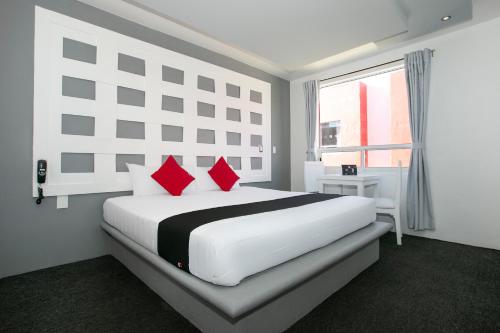 Un dormitorio blanco con una cama grande con almohadas rojas en Hotel Euro Confort,Pachuca, en Pachuca de Soto