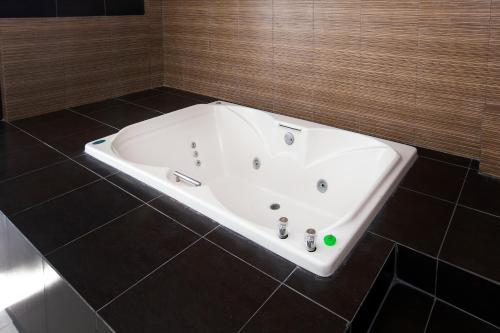 a white bath tub in a bathroom with black tiles at Hotel Euro Confort,Pachuca in Pachuca de Soto