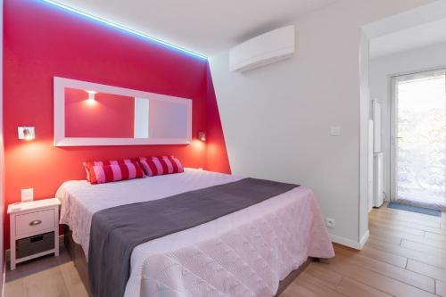 une chambre avec un grand lit avec un mur rouge dans l'établissement Villa Néréides Héliovillage, village naturiste, 45m2,chambre en rez de chaussée avec dressing, au Cap d'Agde