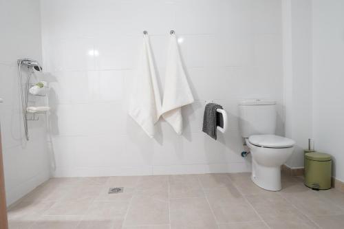 a white bathroom with a toilet and a shower at APARTAMENTOS TURÍSTICOS SAN MIGUEL ARCÁNGEL, S.L. in San Roque