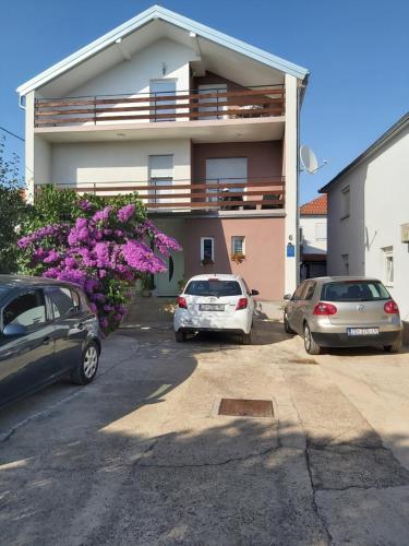 dos autos estacionados en un estacionamiento frente a un edificio en Apartments Toni, en Zadar