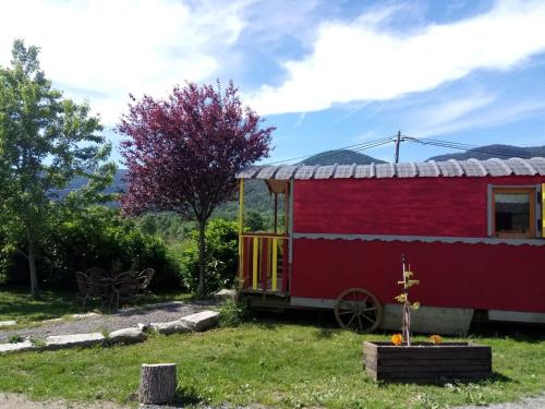 un granero rojo con una rueda en un patio en Le Ranch du Madres en Roquefort-de-Sault
