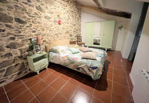 una camera da letto con un letto e un muro di pietra di Maison chaleureuse à Bagnac-sur-Célé 70 m² avec jardin accueillant a Linac