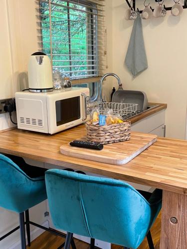 a kitchen with a table with a microwave and blue chairs at The Cabin, Stronua. A beautiful 1 bedroom cabin. in Fort Augustus