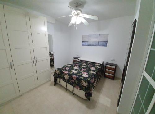 um quarto com uma cama e uma ventoinha de tecto em Apartamento Puerto II em Mazagón