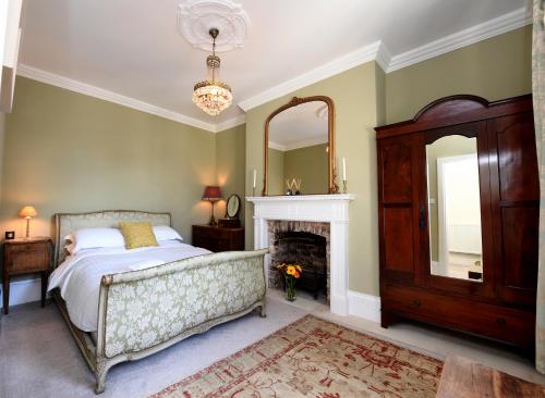 a bedroom with a bed and a fireplace and a mirror at Harrogate Self Catering - West End in Harrogate