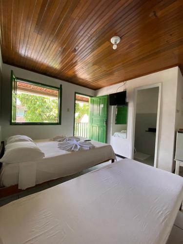 a bedroom with two beds and a wooden ceiling at Pousada Tapuia in Porto Seguro
