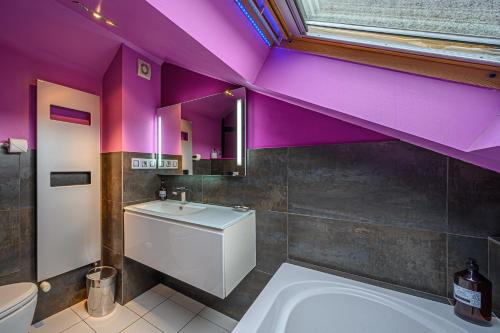 La salle de bains est pourvue de murs violets, d'une baignoire et d'un lavabo. dans l'établissement L'ARAMIS - Appartement Duplex de 110m2 au port de Vannes, à Vannes