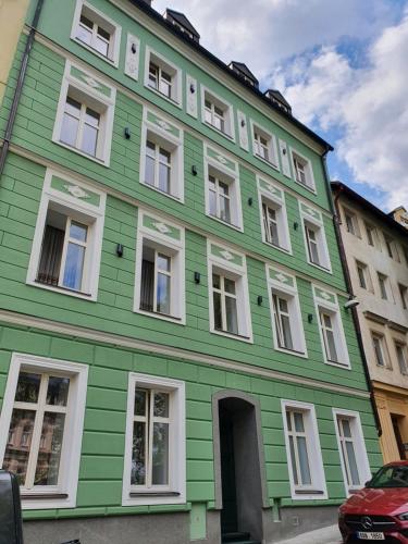 a green building with white windows on a street at Evergreen apartments hotel in Karlovy Vary