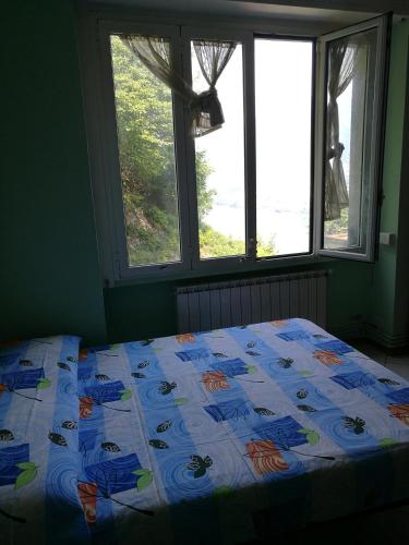 a bed in a bedroom with two windows at LAGO DI COMO LAKE APARTMENT CASA VACANZe in Valbrona