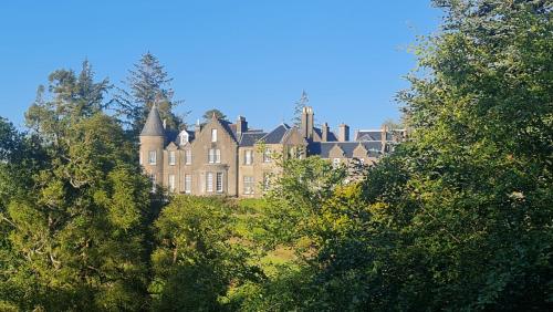 un gran edificio en medio de algunos árboles en Glencruitten House, en Oban