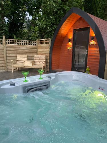 a jacuzzi tub with two martini glasses in it at Paddock Pod - Sleeps 4 & Roofed Over Private Hot Tub in Burnfoot