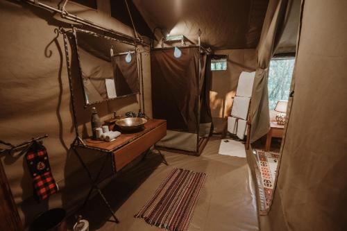 a bathroom in a tent with a sink and a mirror at Mara Olapa Camp in Masai Mara
