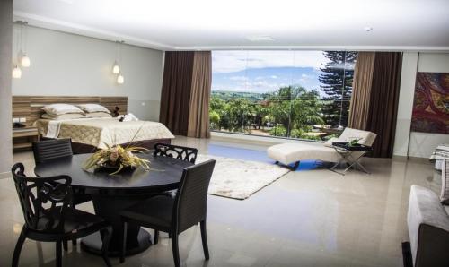 a bedroom with a bed and a table and chairs at Hotel Baeza in Goiatuba