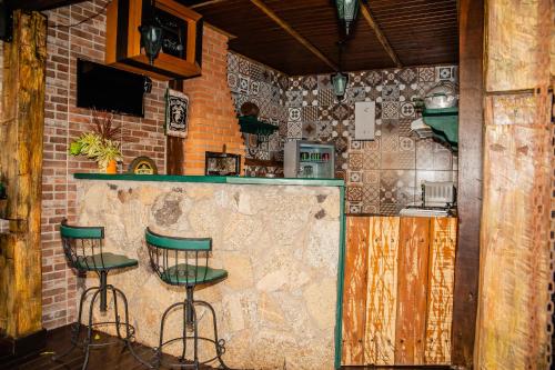 a bar with two green stools in a kitchen at Tiradentes Village in Tiradentes