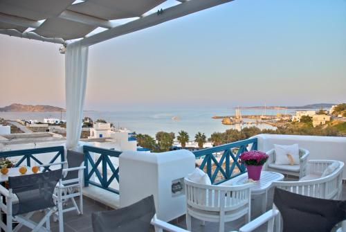 Un balcón con sillas blancas y vistas al océano. en Alexandros Apartments, en Naousa