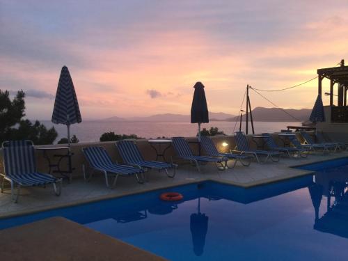 a pool with chairs and a table and a sunset at Panorama Apartments in Marathokampos