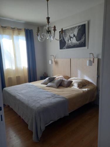 a large bed in a bedroom with a chandelier at La terrasse Majorelle. in Le Passage