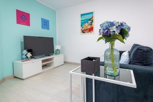 ein Wohnzimmer mit einer Vase aus Blumen auf einem Glastisch in der Unterkunft Dimore Italiane - Boutique Apartments in Corralejo