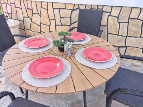 a wooden table with red and white plates on it at Къща Томови,стаи за гости in Devin