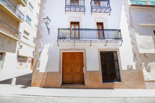 biały budynek z drewnianymi drzwiami i balkonem w obiekcie Casa Paquita w mieście Calpe