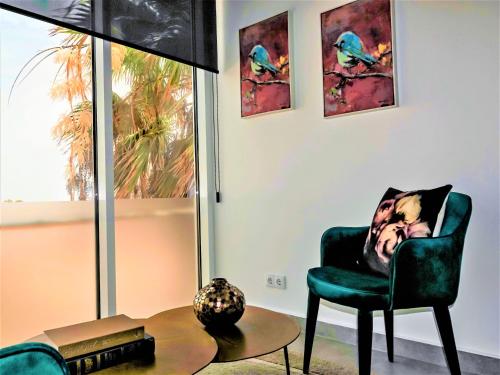 a man sitting in a green chair in a living room at DESIGN SUITES Boutique Hotel - Adults Only in Santa Maria