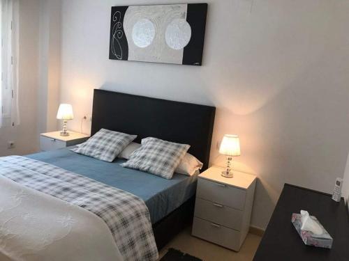 ein Schlafzimmer mit einem Bett mit zwei Nachttischen und zwei Lampen in der Unterkunft Las terrazas de la torre golf Heidi in Murcia