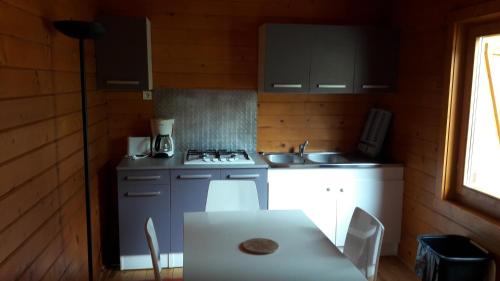a kitchen with a table and a stove and a sink at chalets bois 150m de la plage in Olmeto