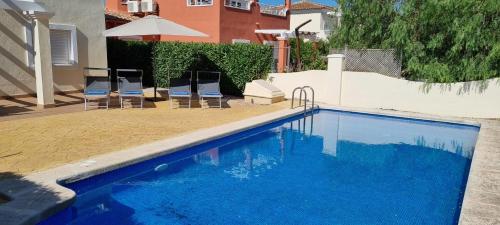 a swimming pool with two chairs and an umbrella at Villa Excelente, with a private pool in Murcia