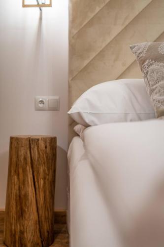 a bed with white sheets and a wooden stump next to it at Dworek nad Jałowcami z Jacuzzi in Biały Dunajec