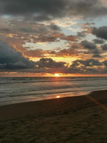 a sunset on a beach with the ocean at Agradable cabaña frente al mar in Parrita